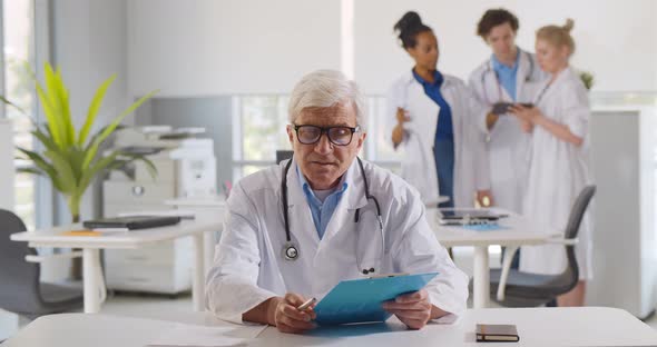 Portrait of Senior Caucasian Male Doctor in Office Consulting Patient on Video Call