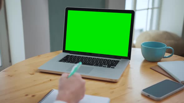 Man Looking at Green Screen on Work Laptop with Chroma Key Mockup in a Workplace