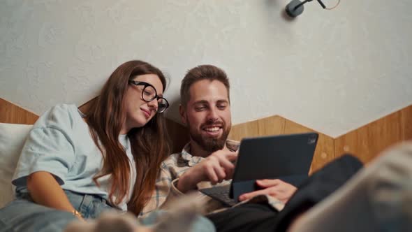 Young couple watching video on tablet in hotel room