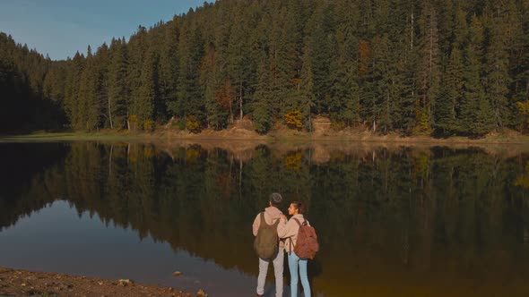 Drone Flight and View From Above of a Couple of Travelers Tourists Standing on Shore of Beautiful