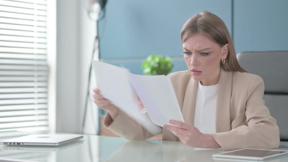 Businesswoman Upset While Reading Documents in Office