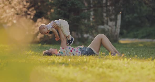 Young Mother Playing with the Baby on the Grass