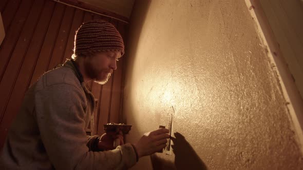 WIDE LOW ANGLE - A handsome professional plasterer using a Japanese trowel