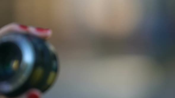 Close-Up of Womans Hand Showing Camera Objective Against Blurred Background