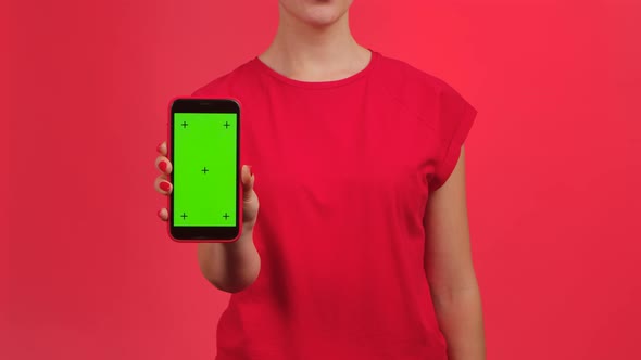 Woman Texting on Smartphone and Demonstrates Phone with Green Workspace Mock Up Screen on Red