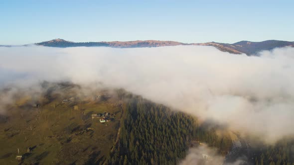 Aerial View of Vibrant Landscape of Foggy Clouds Covering Mountain Hills and Small Scattered Village