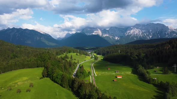 Drone shot of Spring Green Landscape Alps Mountain Peaks With Snow And Pine Forest, Valley With Vill