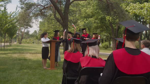 Carefree Diverse Multiethnic Graduates with Diplomas Dancing at Graduation Day