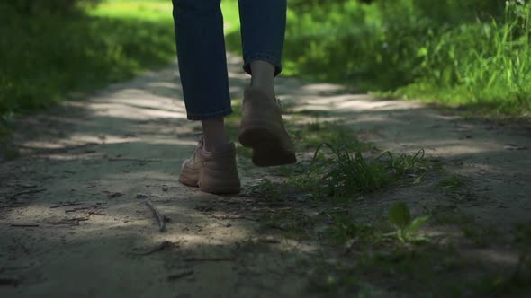 View of Legs of Young Woman Walking on Path in Forest on Summer Day Spbd