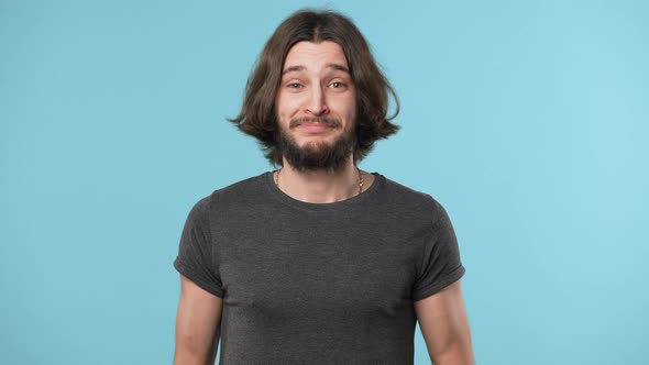 Portrait of Handsome Smiling Guy with Beard and Brown Hair Embarrassing and Waving Hand in