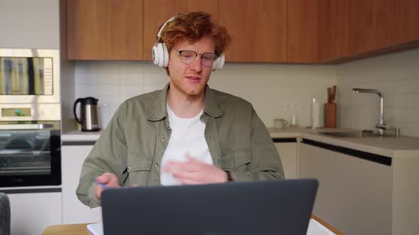 Young Ginger Irish Man in Headphones Listen Business Tutor Coach at Webinar