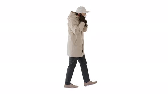 Man Wears Protective Medical Mask and Talks on the Phone Walking on White Background.