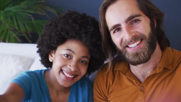 Portrait of mixed race couple taking a selfie while sitting on the couch at home