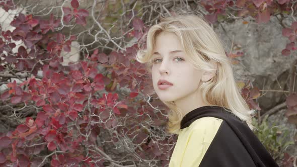 Portrait of a Young Blonde Woman in Unisex Teenage Clothes Against the Backdrop of Mountain