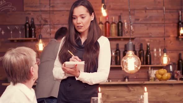 Beautiful Waitress Taking an Order From Old Lady with Glasses