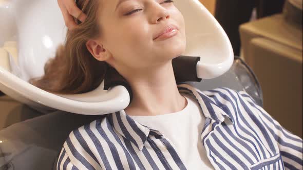 Young Caucasian Female Hairdresser Dyeing Hair To Beautiful Girl with Long Hair