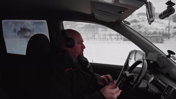 man with laptop in his car working near winter landscape of mountain