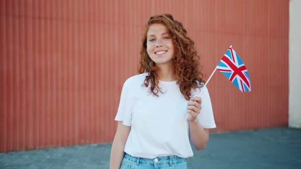 Pretty Redhead Girl Holding British Flag Outdoors Smiling Looking at Camera