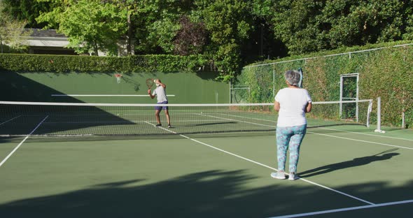 African american senior couple playing tennis on the tennis court on a bright sunny day