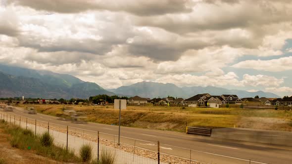 Time lapse taken along a two-lane highway with a dramatic cloudscape overhead and mountains in the d