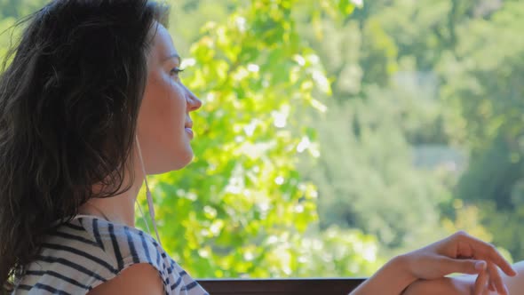 Relaxing Woman on Balcony Listening to Music on Smartphone