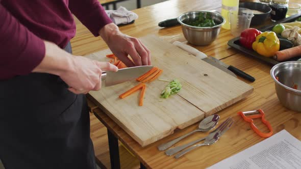 Caucasian male chef cutting carrots in kitchen