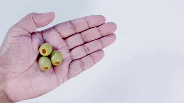 Hand Holding Three Green Olives