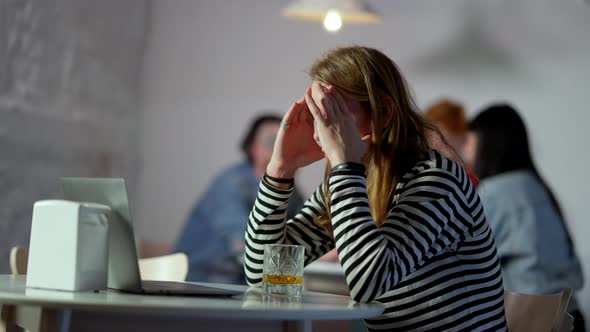 Nervous Young Man Messaging Online on Laptop and Drinking Whiskey in Slow Motion