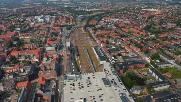 Backwards Fly Above Train Station Located in Centre of Small Danish Town