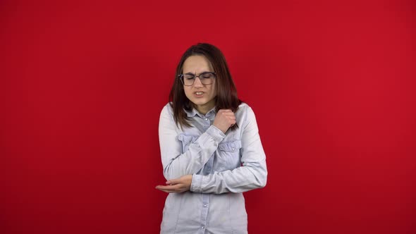 A Young Woman with Glasses Has a Sore Elbow and Holds It in Her Hand