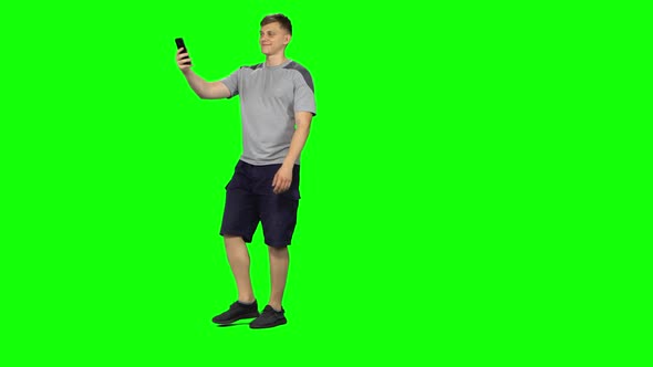 Funny Man Goes and Takes a Selfie with Smartphone on Green Screen at Studio.