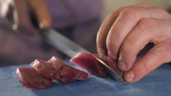 Close Up Macro on the Hands of the Japanese Sushi Sashimi Chef 's Knife Slice the Raw Tuna Salmon