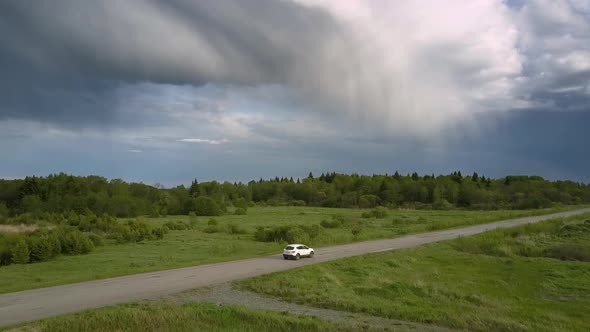 Modern Automobile Drives Along Gray Road Against Forest