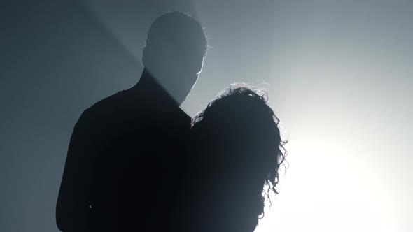 Silhouette Guy and Girl Embracing in Dark Space