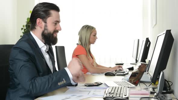 Woman and Man Work on Desktop Computer and Man Rejoices in the Office (Workers)