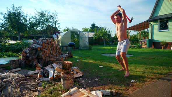 Young Man With Muscular Body Chopping Wood With An Axe. - slow motion