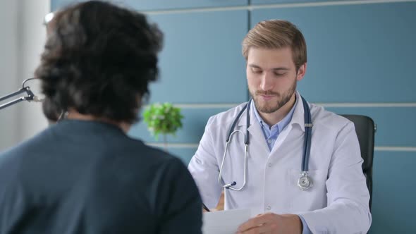 Doctor Talking on Smartphone While Working on Laptop