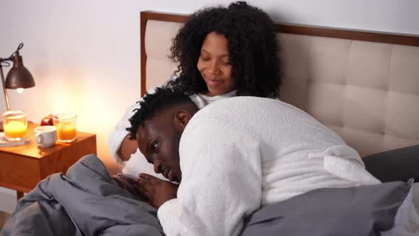 Happy Young African American Father Listening Talking to Pregnant Belly of Smiling Mother As Cute