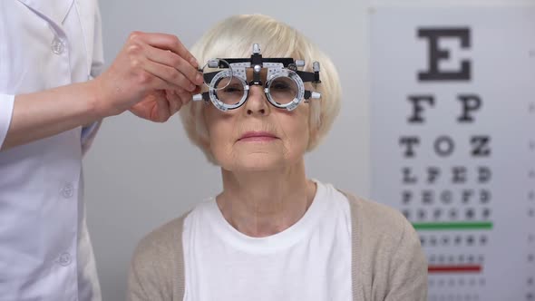 Optician Choosing Correct Lens for Senior Woman in Optical Trial Frame, Checkup