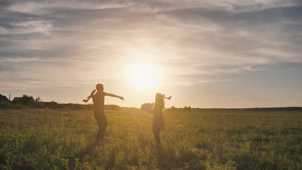 A Guy and a Girl Launch a Paralon Plane at Sunset