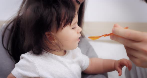 Charming Baby Girl is Fed with a Spoon of Healthy Vegetable Puree