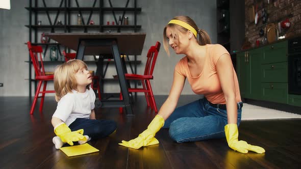Young Mommy and Her Little Son in Yellow Rubber Gloves and Casual Outfit Smiling and Talking