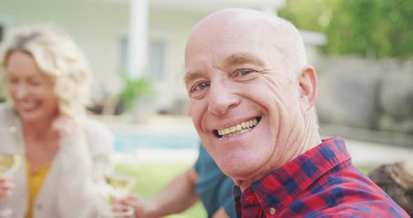 Portrait of happy senior caucasian man having breakfast with family in garden