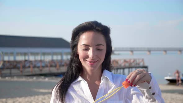 Brunette Woman in White Shirt Blowing Soap Bubbles Outdoors