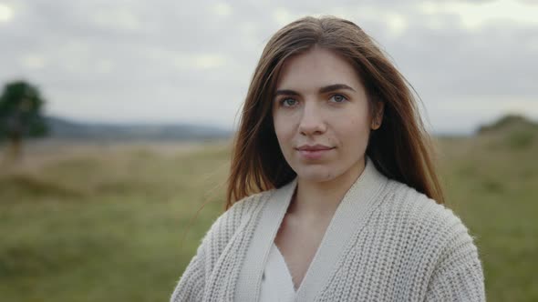 Portrait of Young Woman with Calm Face Posing Outdoors