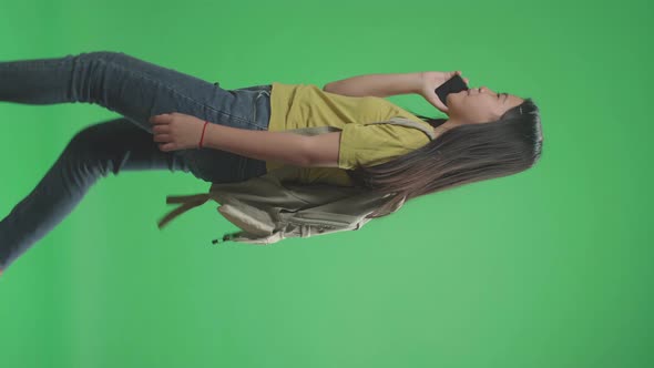 Asian Girl Student Talking On Mobile Phone And Walking To School On Green Screen