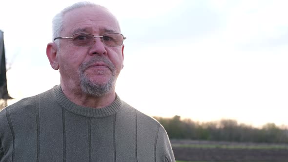 An Old Grandfather with Gray Hair Sitting in the Garden and Talking