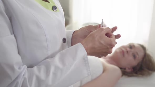 Female Hands Opening Acupuncture Needles at Front As Blurred Young Blond Woman Looking at Camera