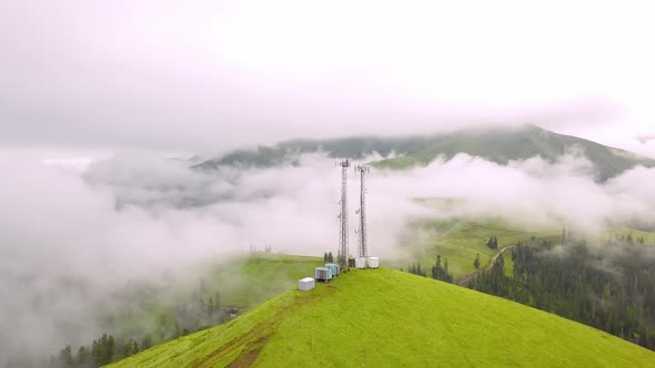 View from drone to GSM tower and radio communications in mountains in clouds.