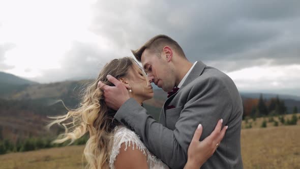 Lovely Young Newlyweds Bride and Groom Embracing Making a Kiss on Mountain Slope Wedding Couple